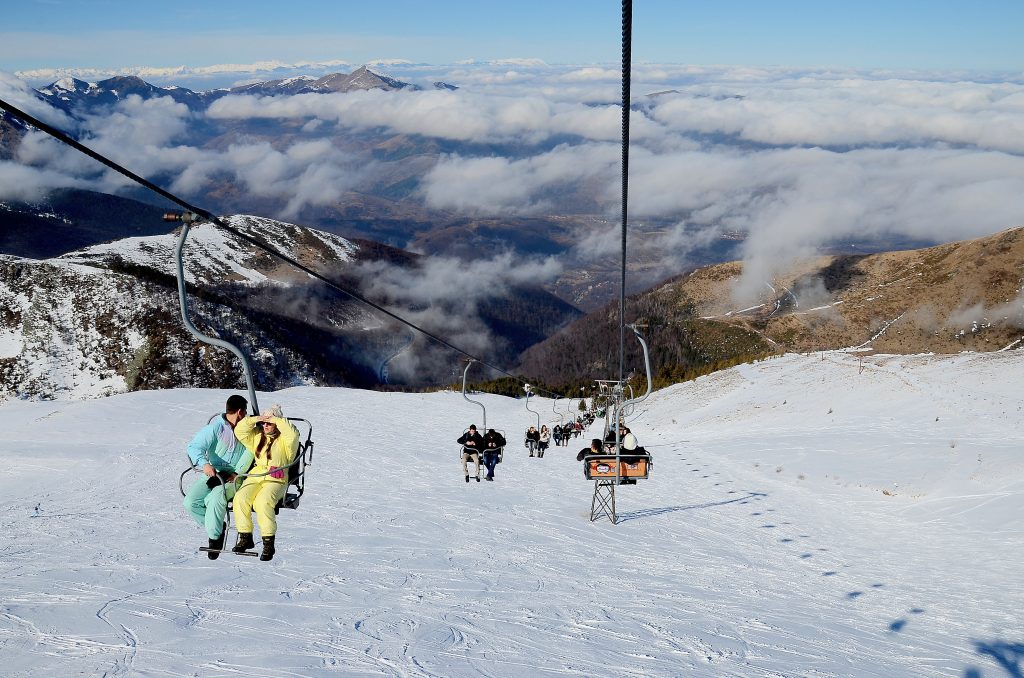 Brezovica Ski Resort covered in snow with skiers and snowy peaks of the Sharr Mountains in the background