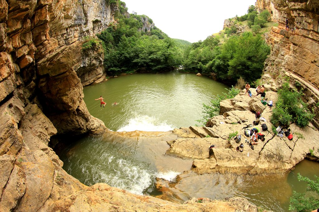 Mirusha waterfall flowing between rocky cliffs and lush greenery in Kosovo